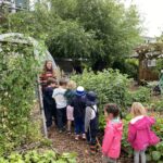 A group of children are in a line following the education assistant as she guides them through the Compost Education Centre site.